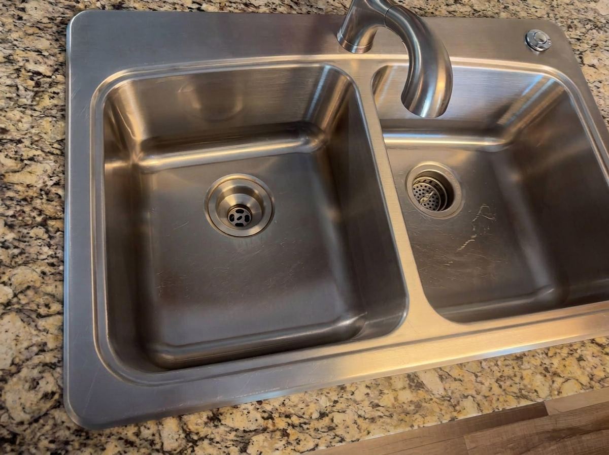 Stainless steel kitchen sink scrubbed to a shine on granite counters